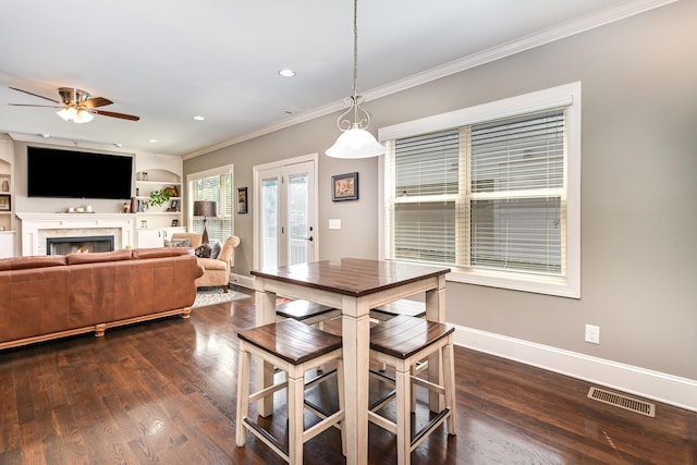 dining space featuring a ceiling fan, crown molding, a lit fireplace, dark wood-type flooring, and recessed lighting