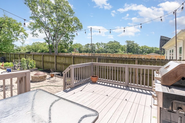deck featuring an outdoor fire pit, a fenced backyard, and grilling area