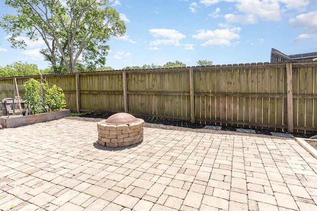 view of patio with an outdoor fire pit, a fenced backyard, and a garden