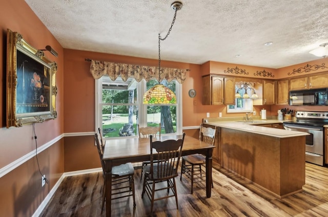 421 Robertson Dr, Smyrna, TN 37167 - kitchen with stainless steel electric range oven, black microwave, a textured ceiling, brown cabinetry, and wood finished floors