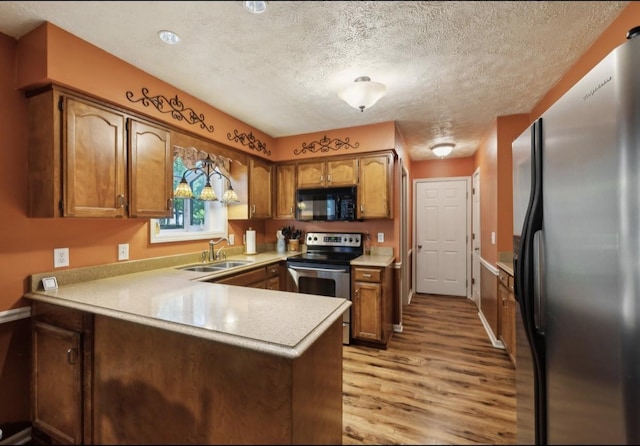 421 Robertson Dr, Smyrna, TN 37167 - kitchen featuring appliances with stainless steel finishes, a sink, a peninsula, light wood-style flooring, and brown cabinets