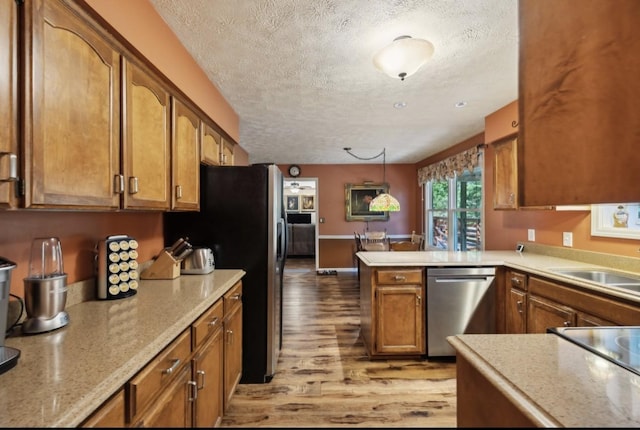 421 Robertson Dr, Smyrna, TN 37167 - kitchen featuring stainless steel appliances, a textured ceiling, light wood finished floors, brown cabinets, and a peninsula