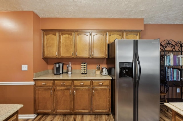 421 Robertson Dr, Smyrna, TN 37167 - kitchen featuring stainless steel refrigerator with ice dispenser, light countertops, brown cabinetry, light wood-style floors, and a textured ceiling