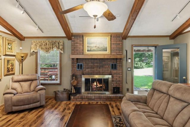 421 Robertson Dr, Smyrna, TN 37167 - living room featuring track lighting, wood finished floors, beamed ceiling, a ceiling fan, and a brick fireplace