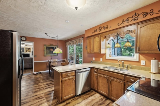 421 Robertson Dr, Smyrna, TN 37167 - kitchen featuring stainless steel appliances, a sink, a peninsula, a textured ceiling, and wood finished floors