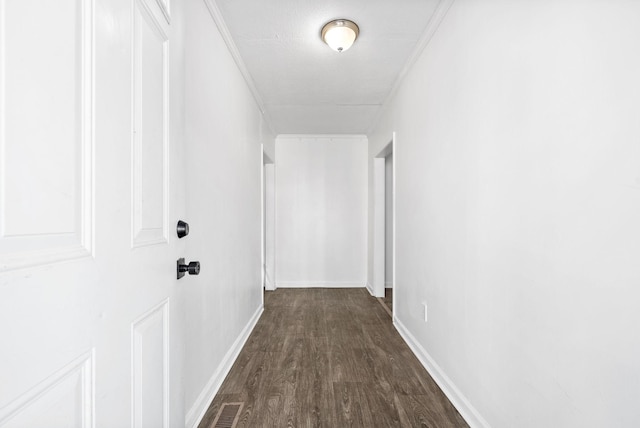 hall with dark wood-style floors, baseboards, and crown molding