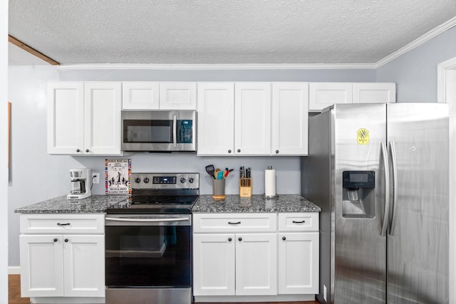 kitchen featuring stainless steel appliances, a textured ceiling, white cabinetry, crown molding, and dark stone countertops