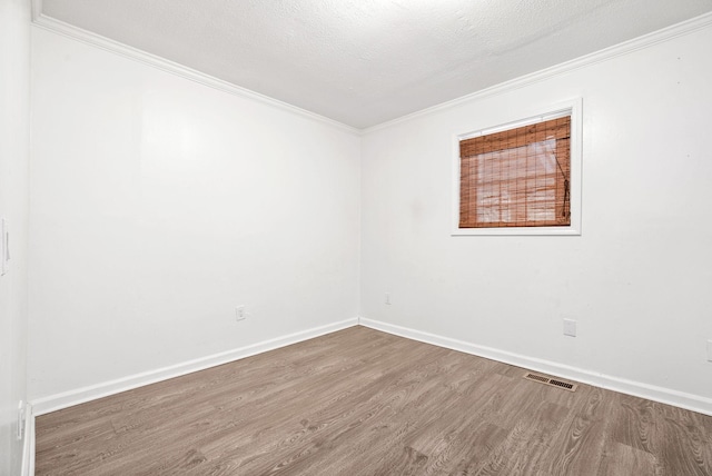 unfurnished room with ornamental molding, wood finished floors, and baseboards