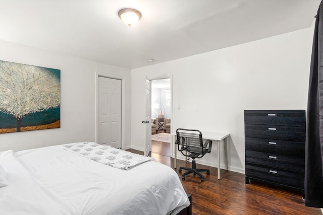 bedroom with wood finished floors, baseboards, and a closet