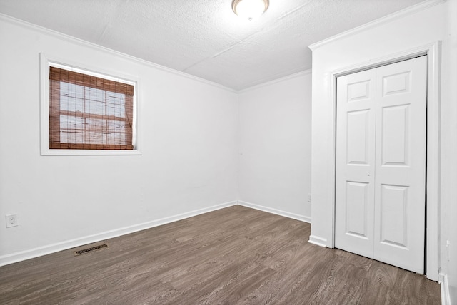 unfurnished room with crown molding, dark wood-type flooring, a textured ceiling, and baseboards