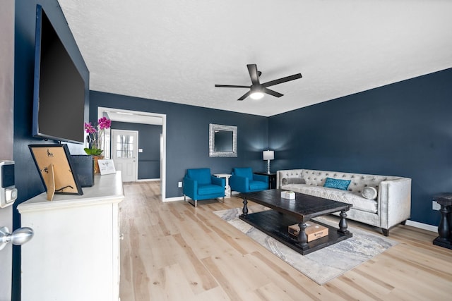 living area with a ceiling fan, light wood-style flooring, and baseboards