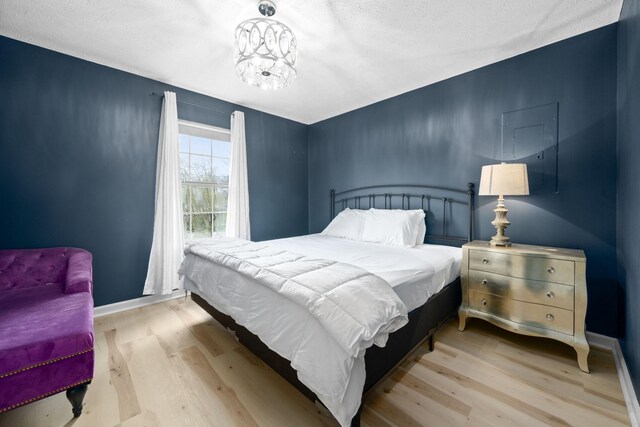bedroom featuring wood finished floors, baseboards, and a textured ceiling