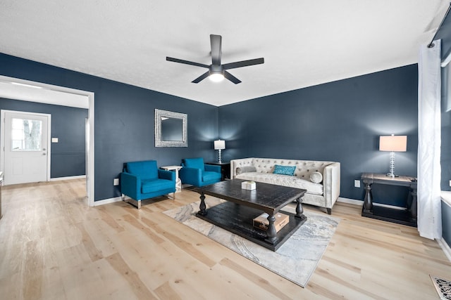 living room featuring ceiling fan, wood finished floors, and baseboards