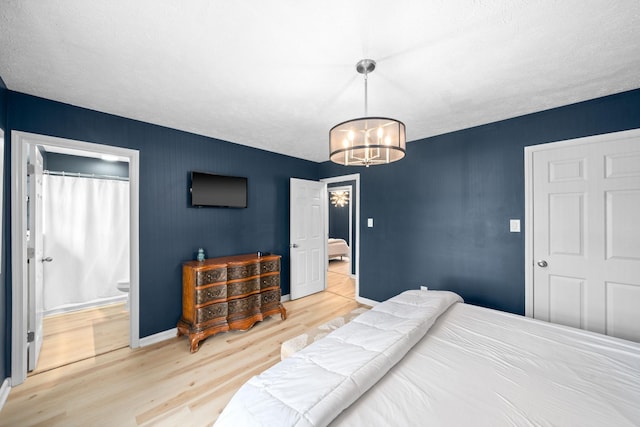 bedroom with a chandelier, light wood-style floors, baseboards, and ensuite bathroom