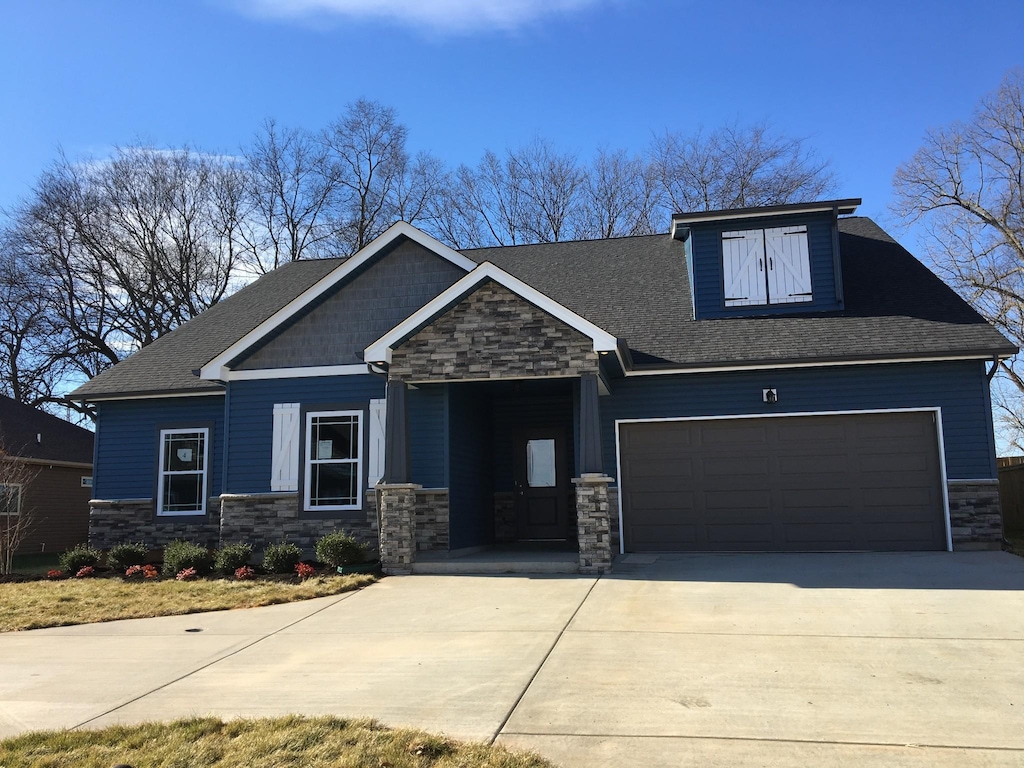 craftsman-style home featuring stone siding, concrete driveway, a shingled roof, and a garage