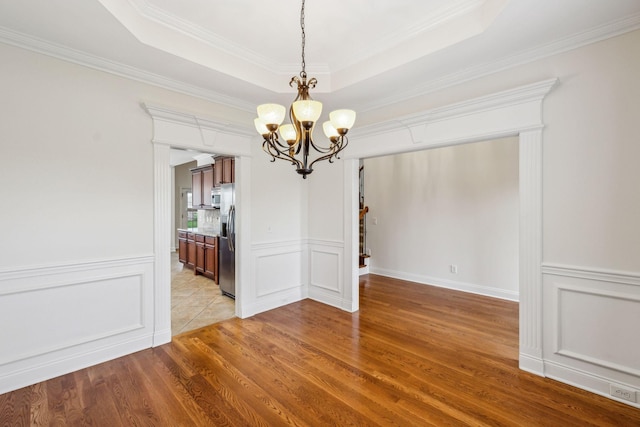 1015 Kingman Ave, Murfreesboro, TN 37129 - unfurnished dining area featuring a chandelier, wood finished floors, a decorative wall, crown molding, and a tray ceiling