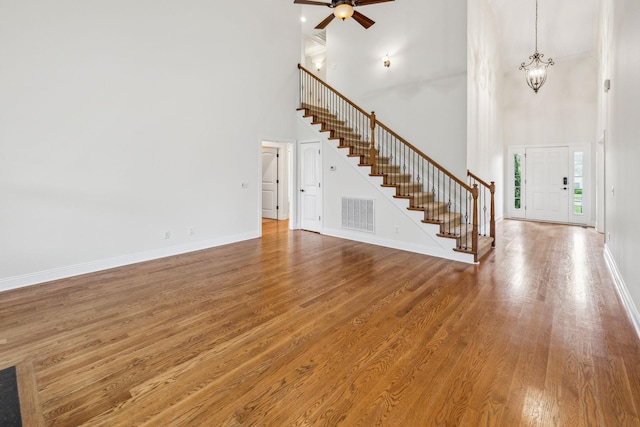 1015 Kingman Ave, Murfreesboro, TN 37129 - unfurnished living room with a towering ceiling, stairway, a ceiling fan, wood finished floors, and baseboards