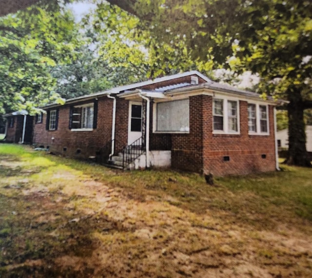 view of front of property with crawl space, brick siding, entry steps, and a front lawn