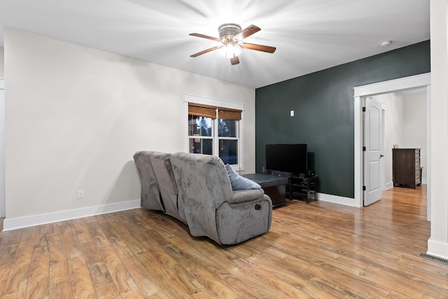 living area with ceiling fan, light wood-style flooring, and baseboards