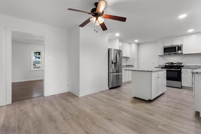 2851 Cooper Creek Rd, Woodlawn, TN 37191 - kitchen featuring appliances with stainless steel finishes, ceiling fan, decorative backsplash, light stone counters, and white cabinetry