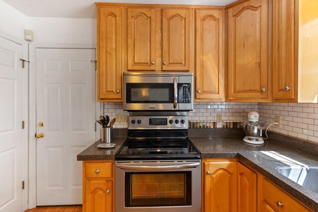 7104 Elrod Rd, Fairview, TN 37062 - kitchen with stainless steel appliances, tasteful backsplash, dark stone counters, and brown cabinetry