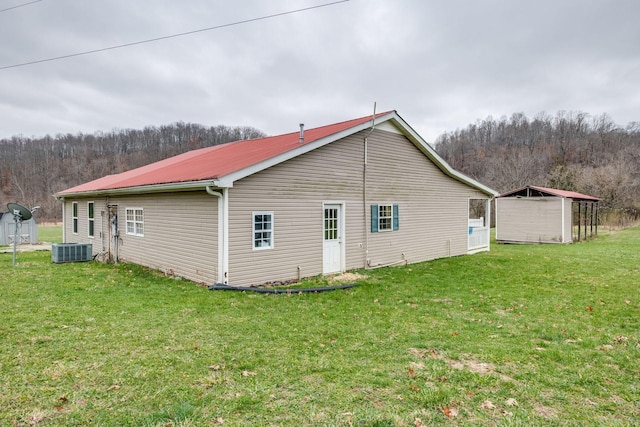 8310 Dog Creek Rd, Primm Springs, TN 38476 - view of property exterior with a yard, central AC, a wooded view, metal roof, and an outdoor structure