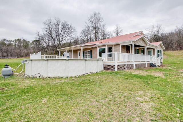 8310 Dog Creek Rd, Primm Springs, TN 38476 - rear view of property with covered porch, metal roof, a yard, and an outdoor pool