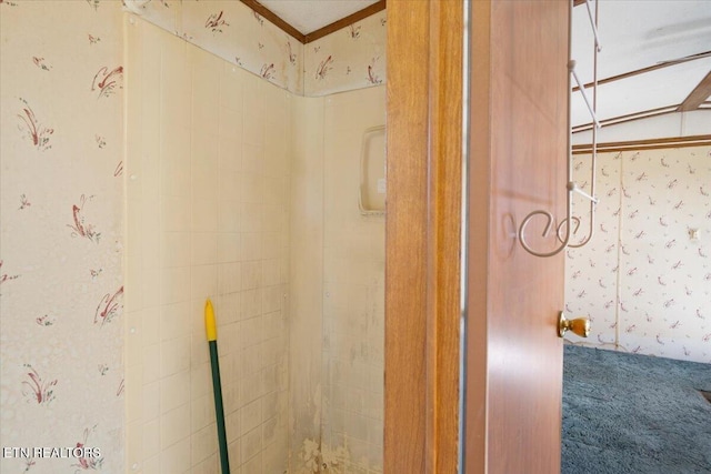 bathroom view of wallpapered walls, carpet flooring, and a tile shower