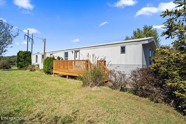 rear view of house featuring a wooden deck and a lawn