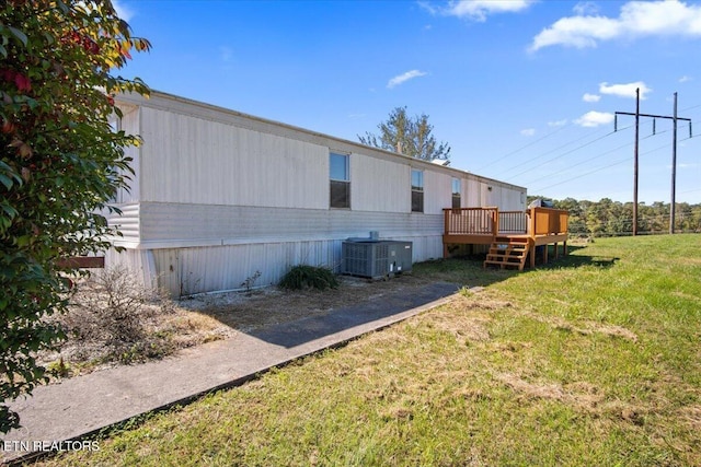 view of home's exterior featuring central AC unit, a deck, and a lawn