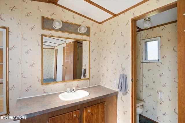 bathroom featuring toilet, ornamental molding, vanity, and wallpapered walls