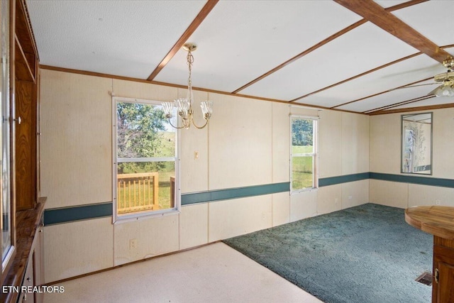carpeted empty room featuring plenty of natural light, a chandelier, a ceiling fan, and wood walls