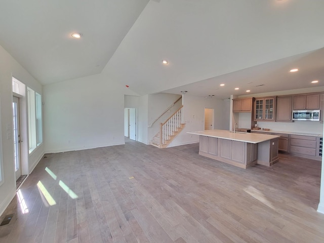 832 Westchester Cir, Hendersonville, TN 37075 - kitchen with stainless steel microwave, an island with sink, lofted ceiling, light wood finished floors, and glass insert cabinets