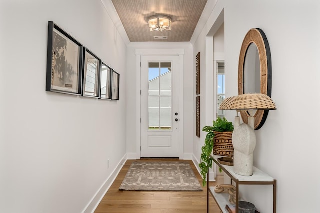 entryway with wood finished floors, baseboards, a chandelier, and crown molding