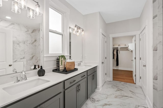 full bathroom featuring marble look tiles, double vanity, and a walk in closet