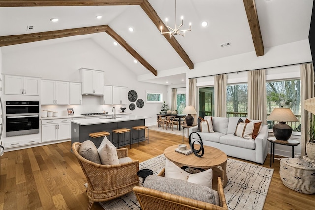 living area with high vaulted ceiling, a chandelier, beamed ceiling, light wood-style flooring, and recessed lighting