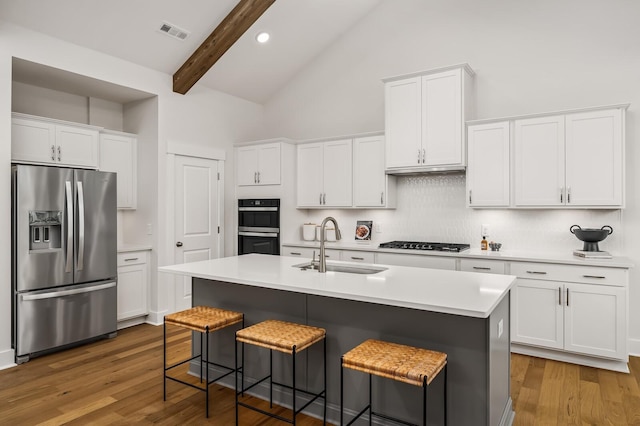 kitchen with stainless steel fridge with ice dispenser, a sink, stovetop, backsplash, and a breakfast bar area