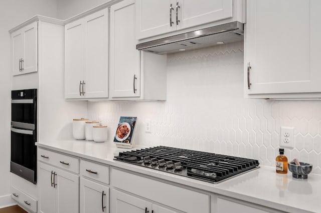 kitchen featuring under cabinet range hood, stainless steel gas cooktop, tasteful backsplash, and light countertops