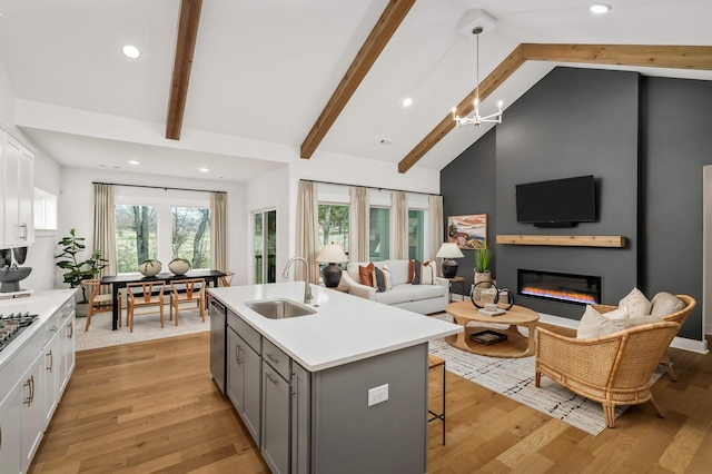kitchen with a sink, stainless steel dishwasher, gray cabinets, high vaulted ceiling, and light countertops