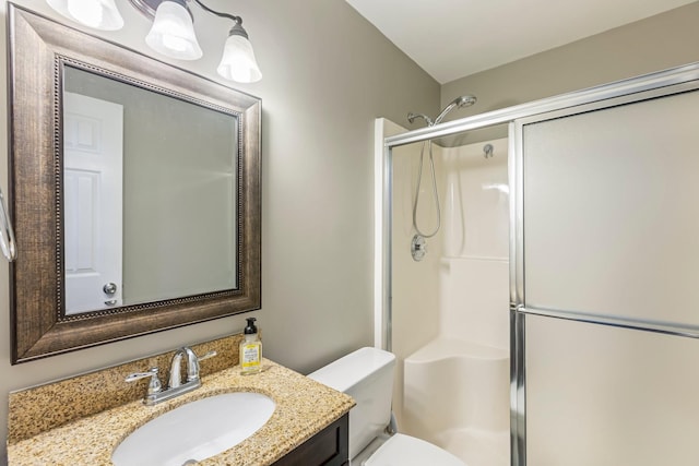 full bathroom featuring a stall shower, toilet, and vanity