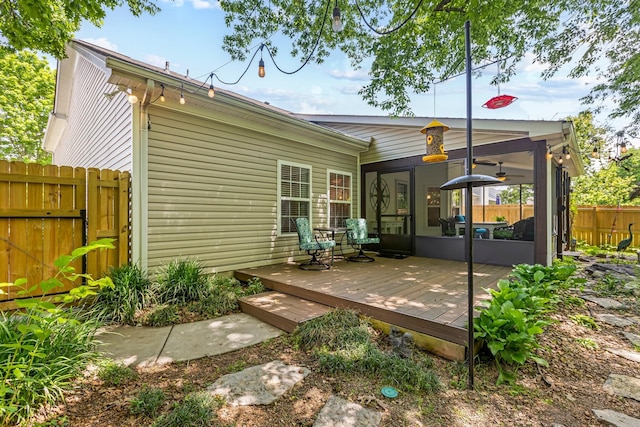 back of house with a sunroom, fence, and a wooden deck