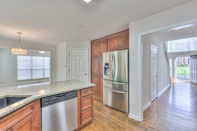 408 Parish Pl, Franklin, TN 37067 - kitchen featuring stainless steel appliances, light wood-style floors, brown cabinetry, and light stone counters
