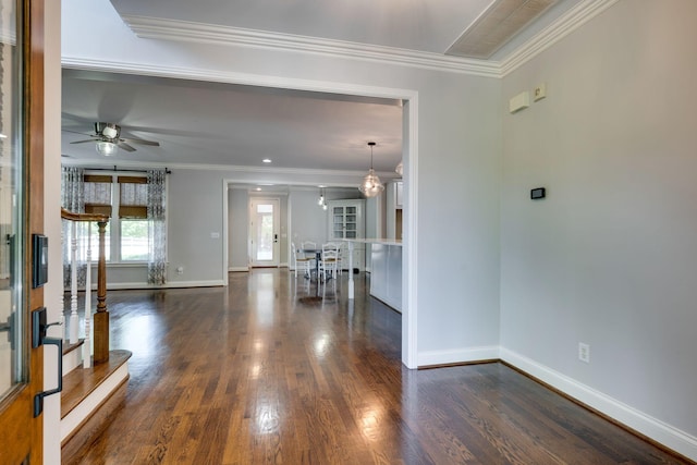 unfurnished living room with dark wood-type flooring, baseboards, a ceiling fan, and crown molding