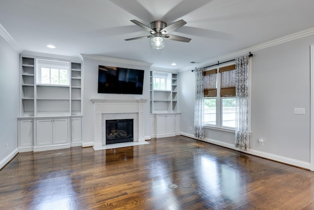 unfurnished living room with a ceiling fan, built in features, crown molding, a fireplace, and wood finished floors