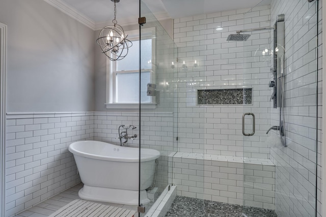 bathroom with a chandelier, a freestanding tub, a shower stall, crown molding, and a wainscoted wall