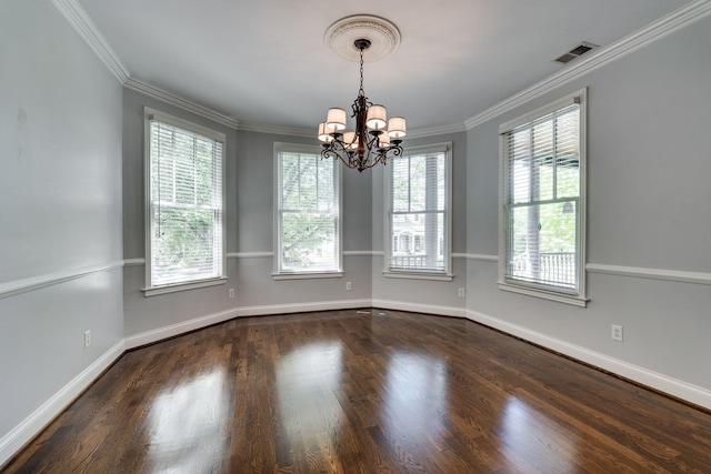 unfurnished room with a chandelier, healthy amount of natural light, wood finished floors, crown molding, and baseboards
