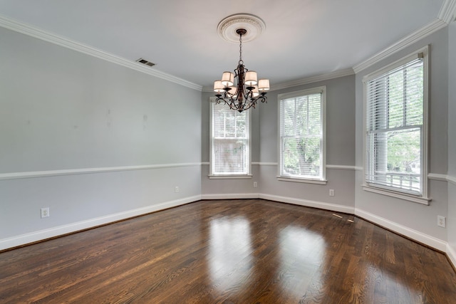 empty room with a chandelier, plenty of natural light, wood finished floors, and crown molding