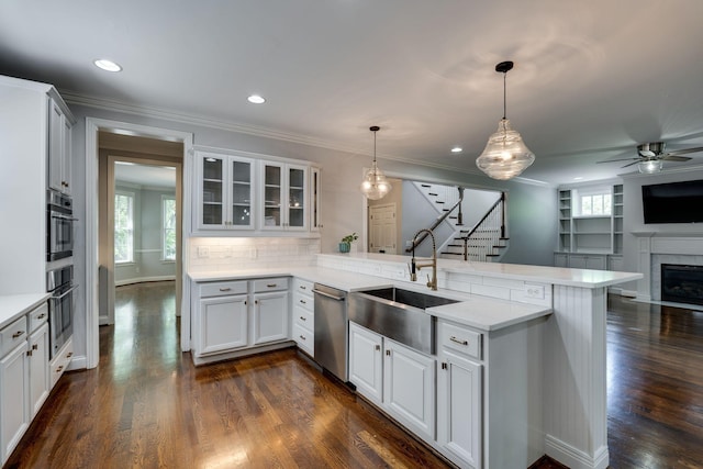 kitchen featuring dishwasher, a peninsula, a sink, open floor plan, and ceiling fan