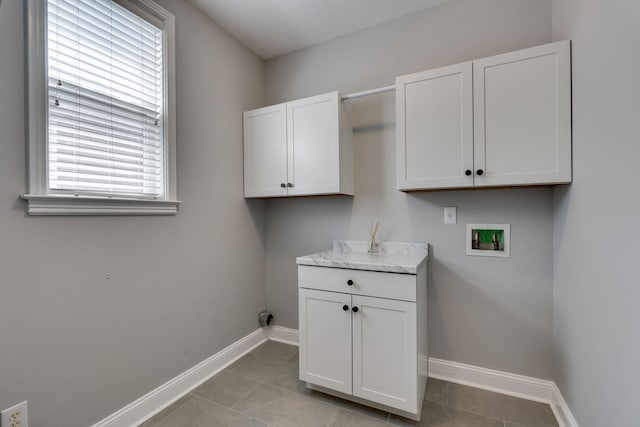 laundry area with hookup for a washing machine, baseboards, light tile patterned floors, and cabinet space