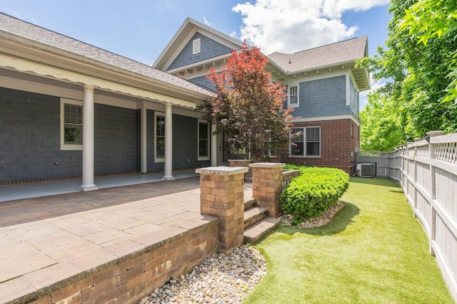 rear view of property with central air condition unit, roof with shingles, and brick siding